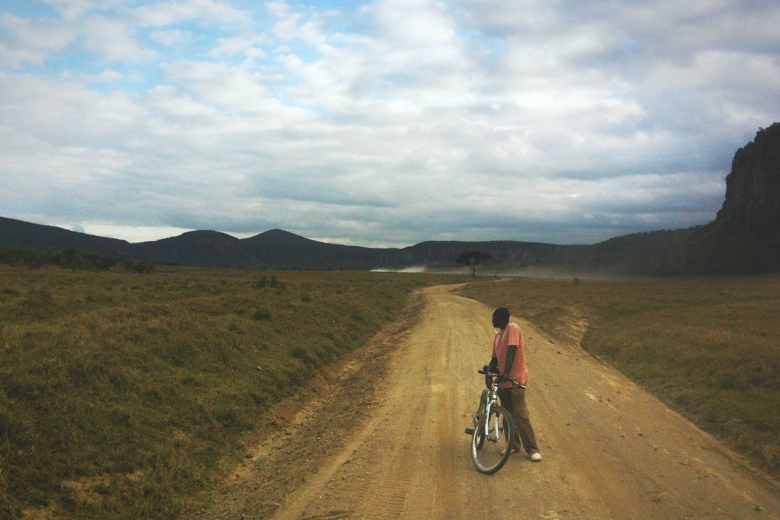 man standing on brown road path